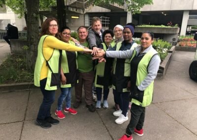 Ein Team von Reinigungskräften das stolz seine Hände in die Mitte zusammen ballt als Zeichen von Teamwork.